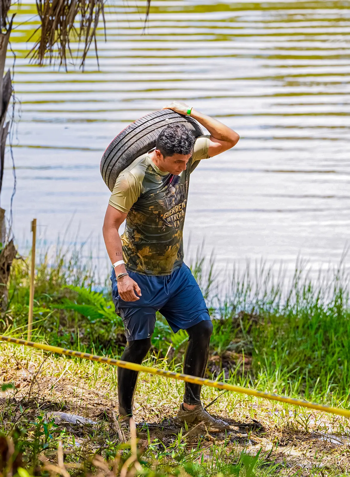 Atleta cargando una llanta junto al lago